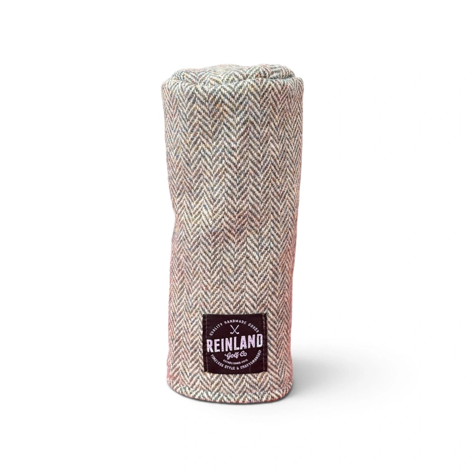 A golf club headcover made of a textured herringbone tweed fabric in beige, and gray tones, featuring a black patch with the Reinland Golf Co logo.