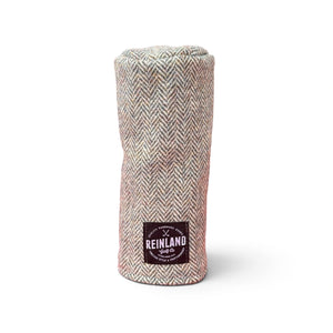 A golf club headcover made of a textured herringbone tweed fabric in beige, and gray tones, featuring a black patch with the Reinland Golf Co logo.